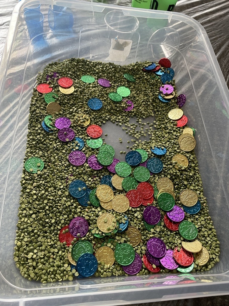 plastic bin filled with split green peas and colorful plastic coins