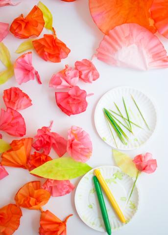 orange coffee filters made to look like flowers with paper plates and green and yellow markers