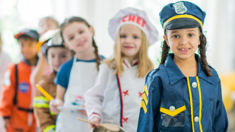 5 children in a line dressed in career costumes; police officer, doctor, vet, firefighter, astronaut