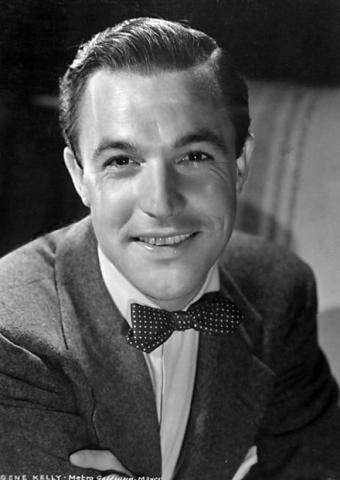 A black and white photo of actor Gene Kelly, wearing a suit and bowtie