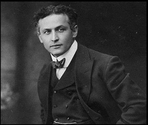 A black and white photo of Houdini looking to the viewer's right, a Hungarian man with curly hair brushed back, wearing the usual dark suit and bowtie that men wore in the 1900's