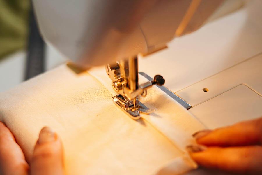 A piece of fabric being sewn in a sewing machine.