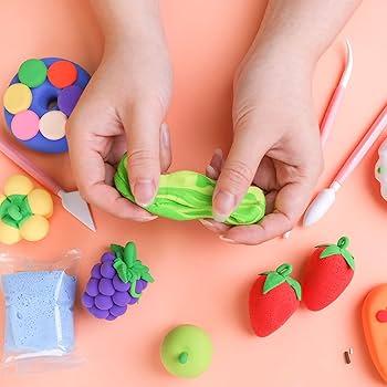 Child stretching green and yellow clay surrounded by clay sculpted into fruit